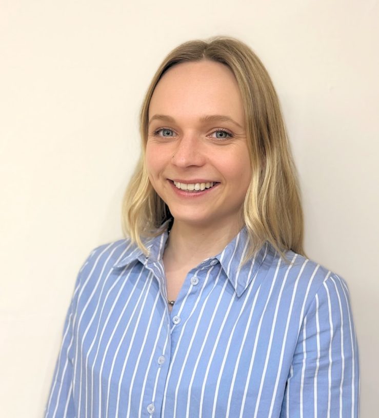 A photo of Gabrielle Morse, who has long blonde hair, loosely hanging behind her shoulders, she is smiling