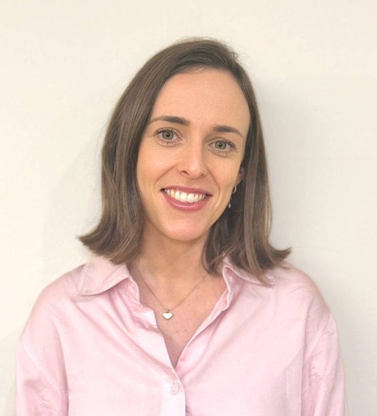 A photo of Alice Twomey, who has a short, brown bob. She is smiling and wearing a light pink shirt.