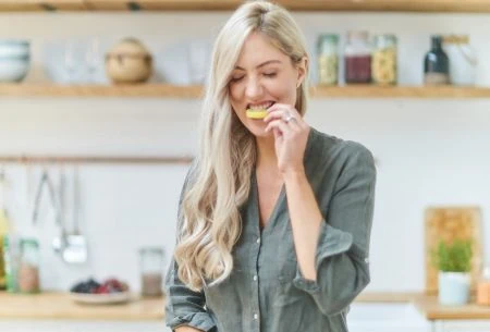 Megan Rossi in kitchen slicing a lemon and eating it