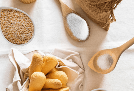 Bench top with mixed grains such as rice, bread etc displayed in an assortment of wooden bowls and spoons